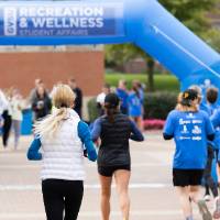 Participants nearing finish line showing blue arch